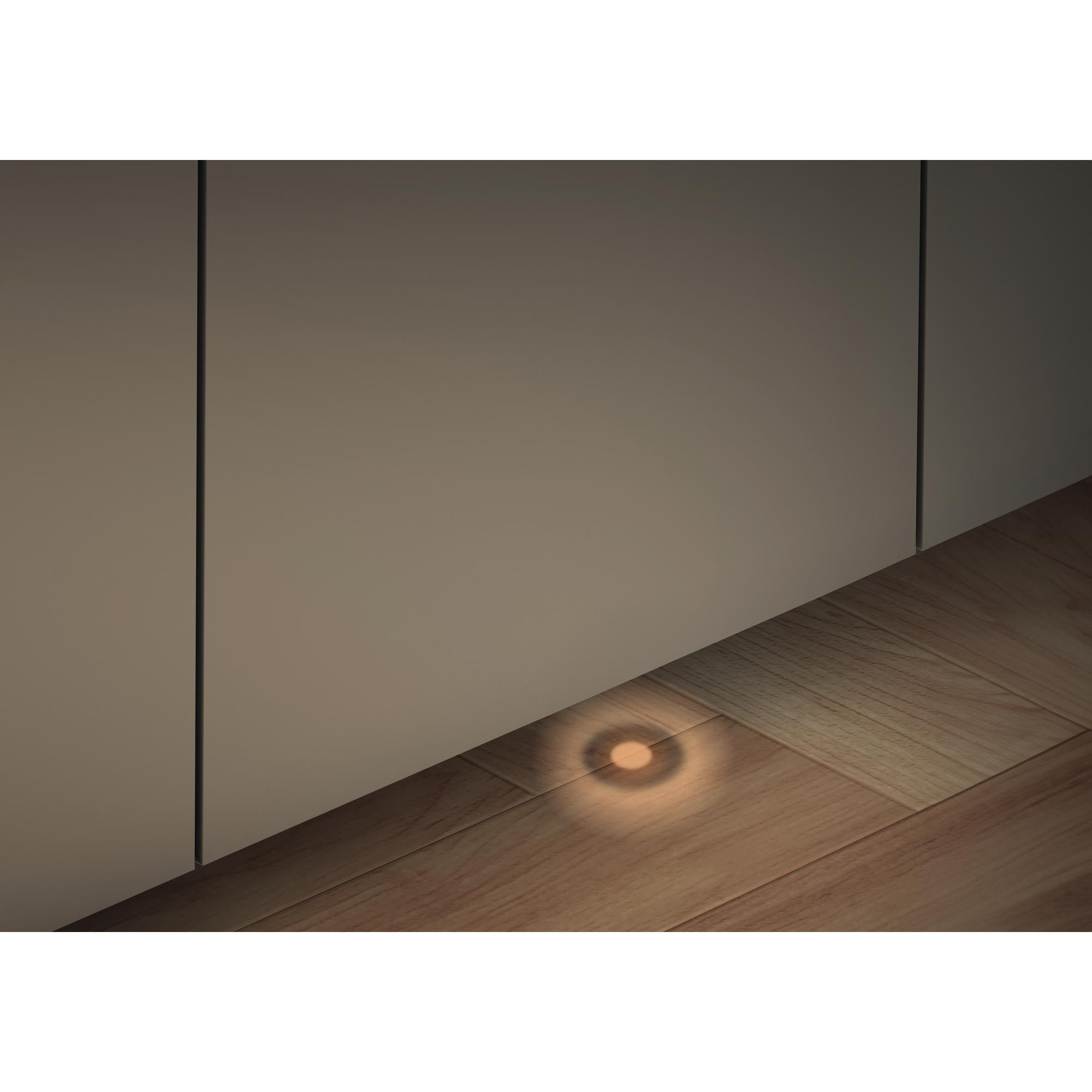 Ein kleiner Bodenspot beleuchtet einen Holzboden nahe einer Wand.