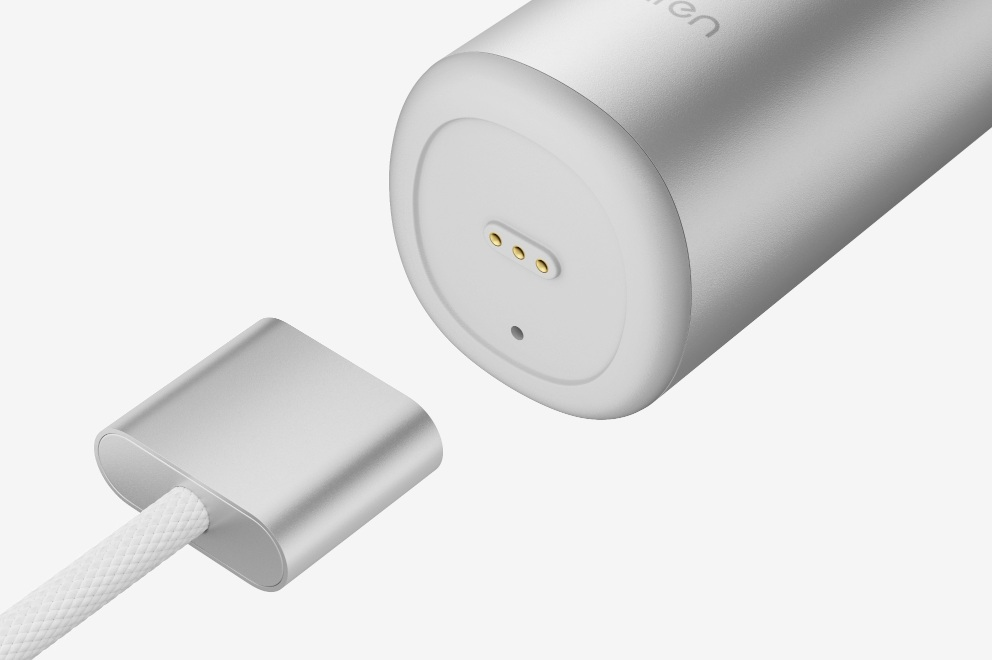 Srebrny kabel ładujący zbliża się do portu ładowania z trzema pinami.