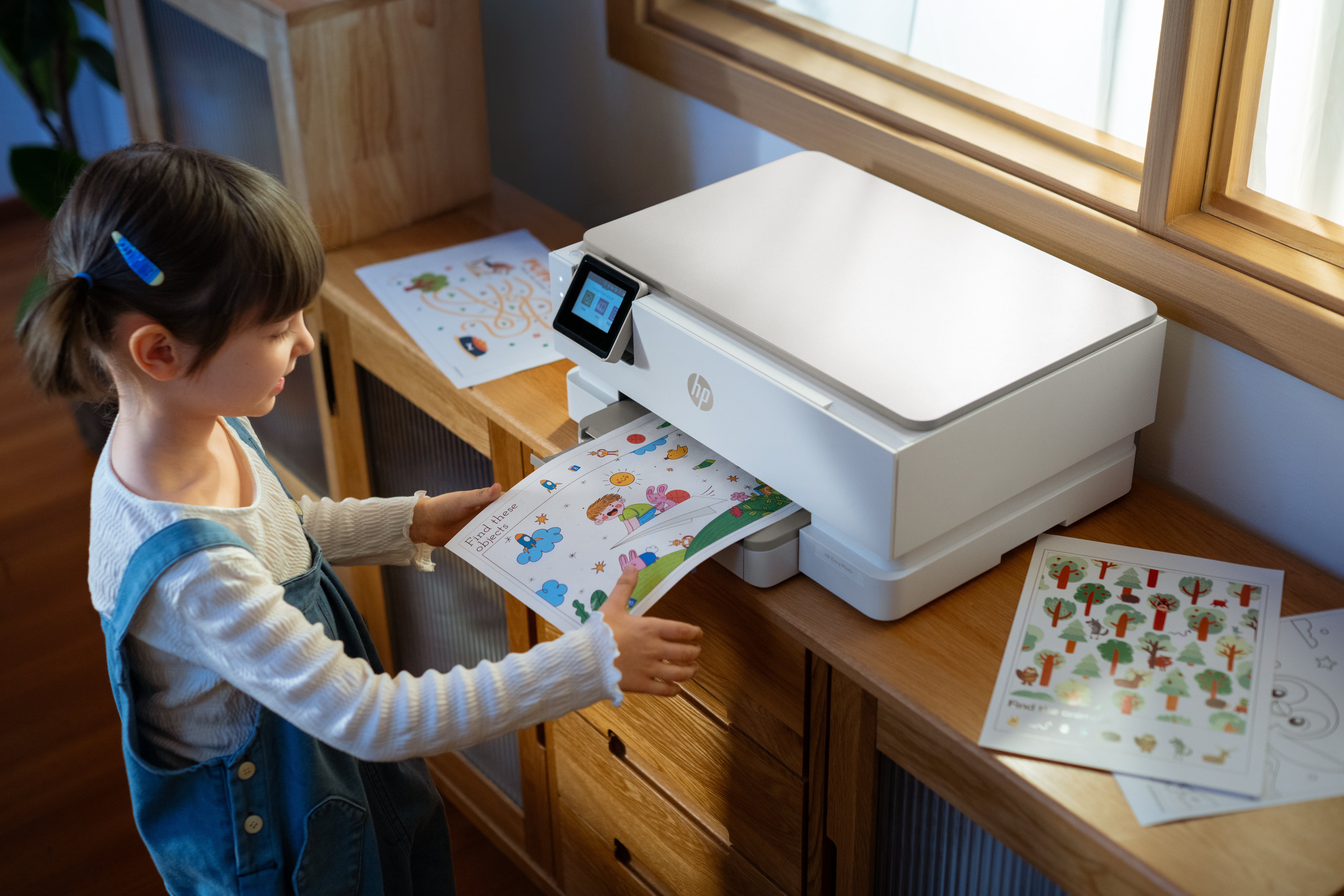 Una bambina prende un foglio colorato da una stampante.