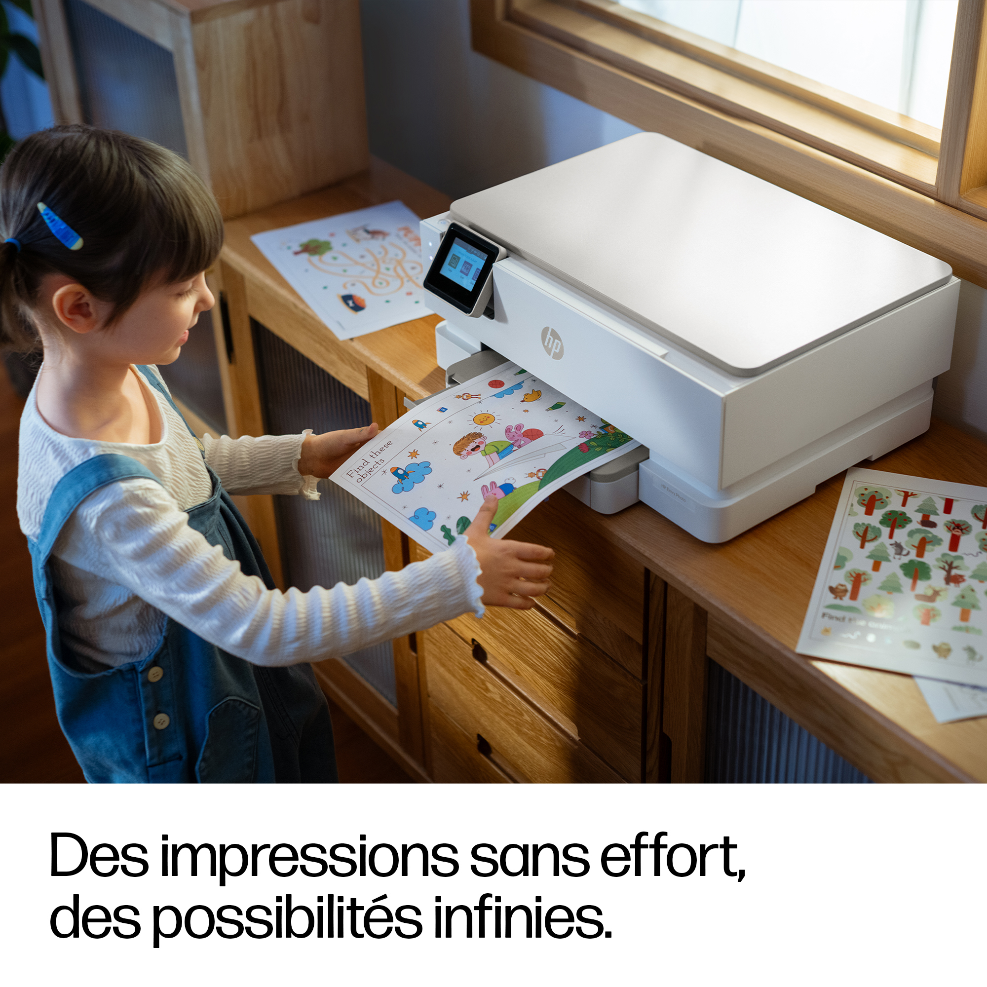 Un bambino prende un foglio di gioco colorato da una stampante HP bianca.