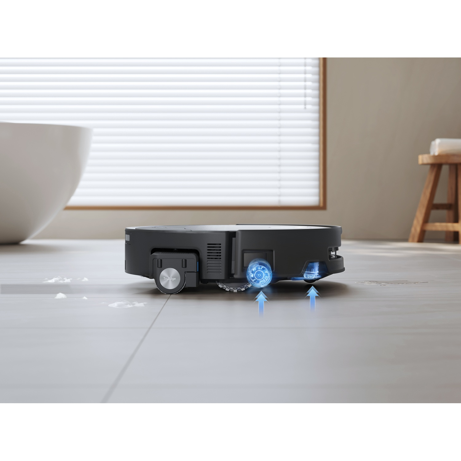 Un robot aspirapolvere nero pulisce un pavimento chiaro. Frecce blu indicano aspirazione.