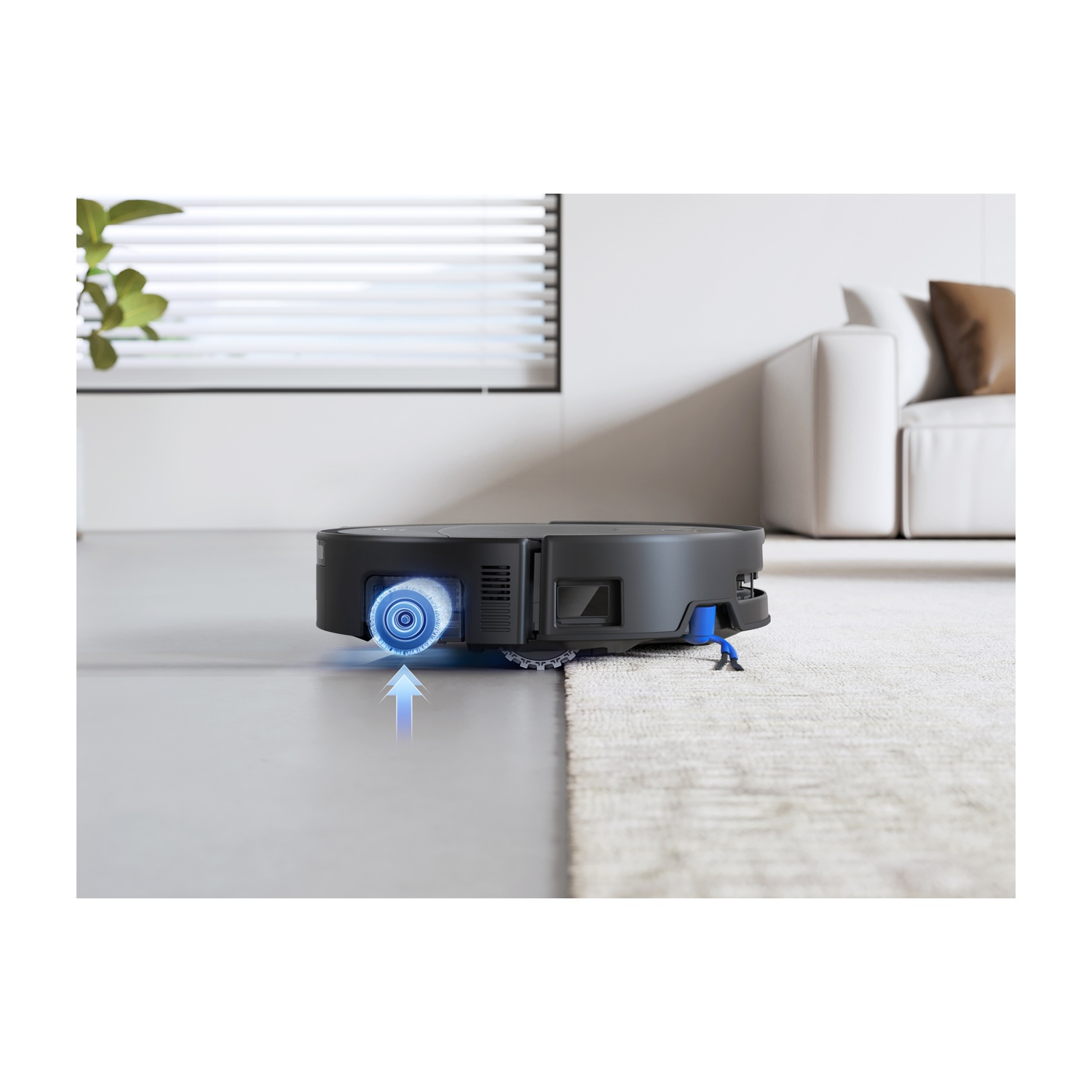 Un robot aspirapolvere nero pulisce un tappeto, con spazzole blu e una freccia.
