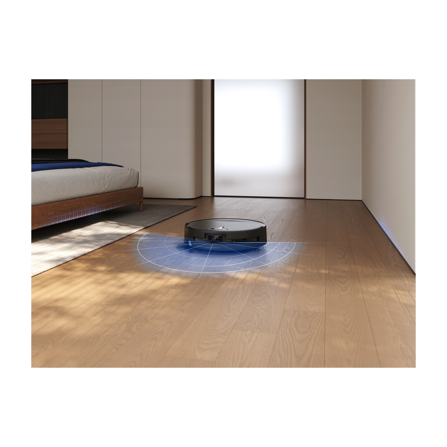 Un robot aspirapolvere nero rotondo pulisce un pavimento in legno accanto a un letto.