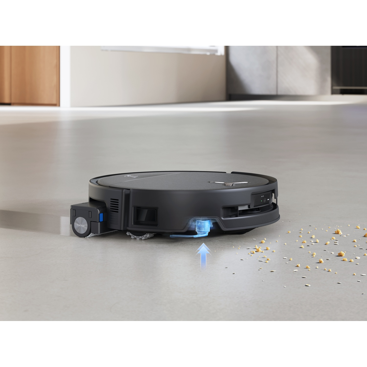 Un robot aspirapolvere nero pulisce briciole su un pavimento grigio.