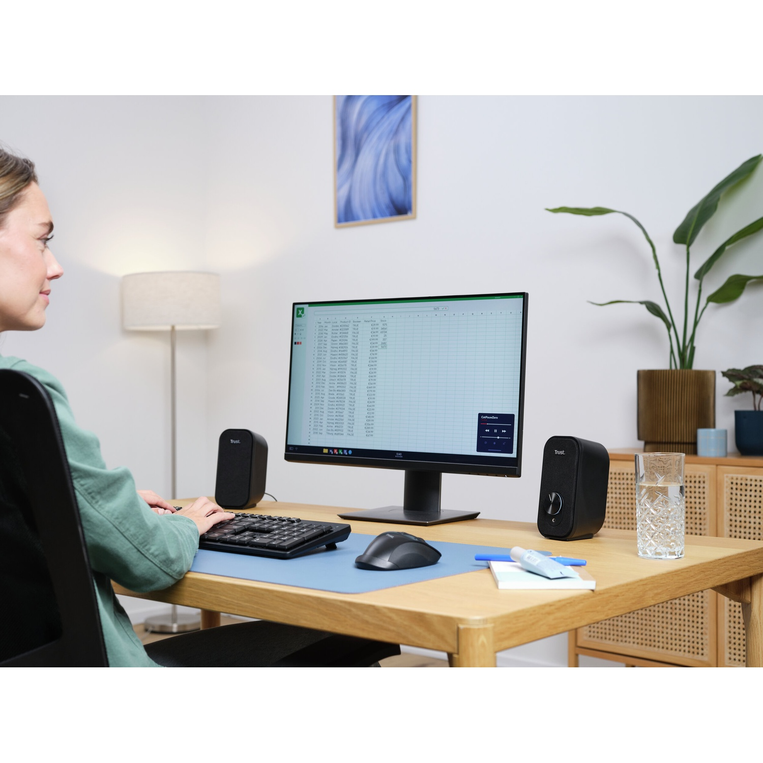 Donna alla scrivania con monitor, tastiera, mouse e altoparlanti.