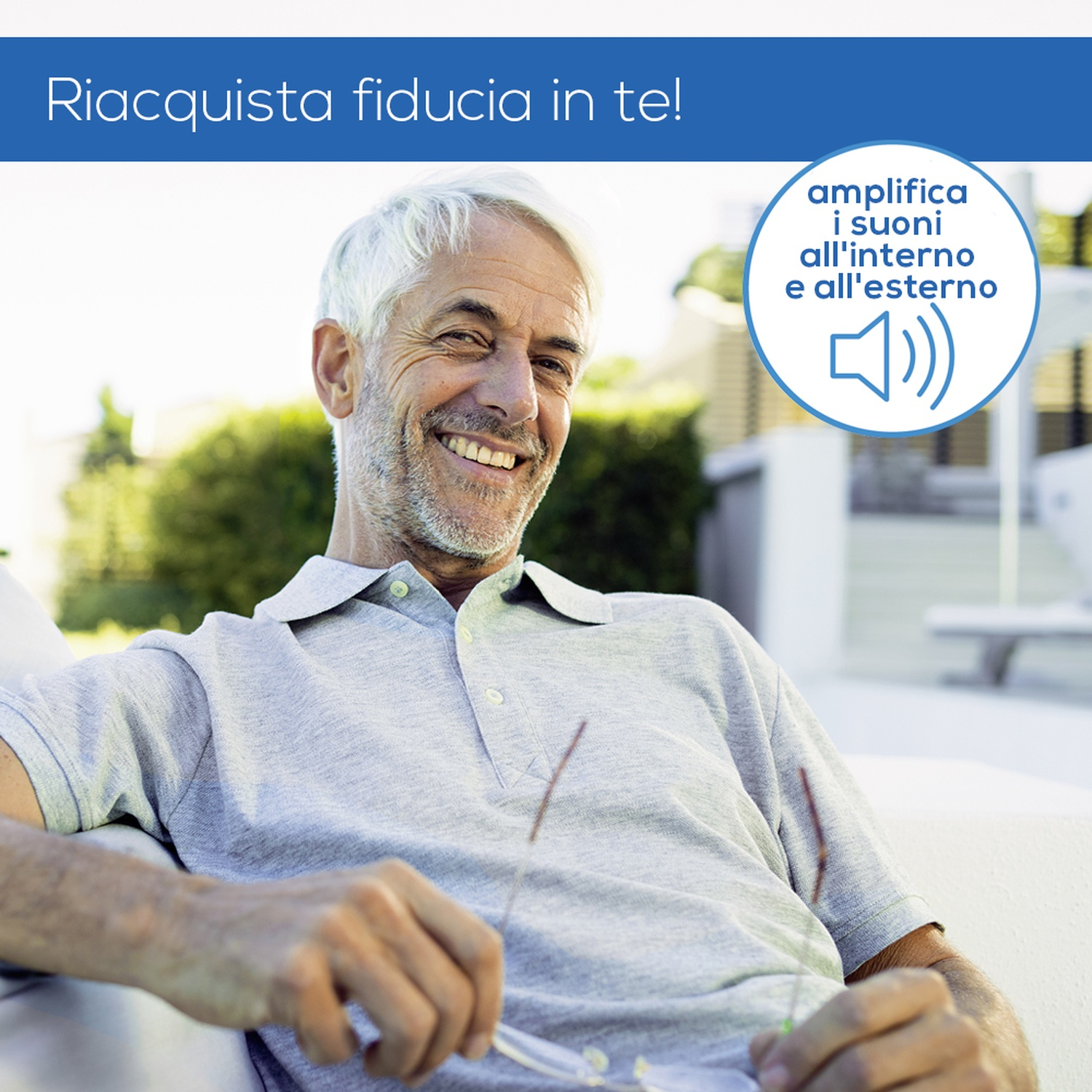 Un uomo anziano sorridente con capelli grigi è seduto all'aperto con una polo grigia.