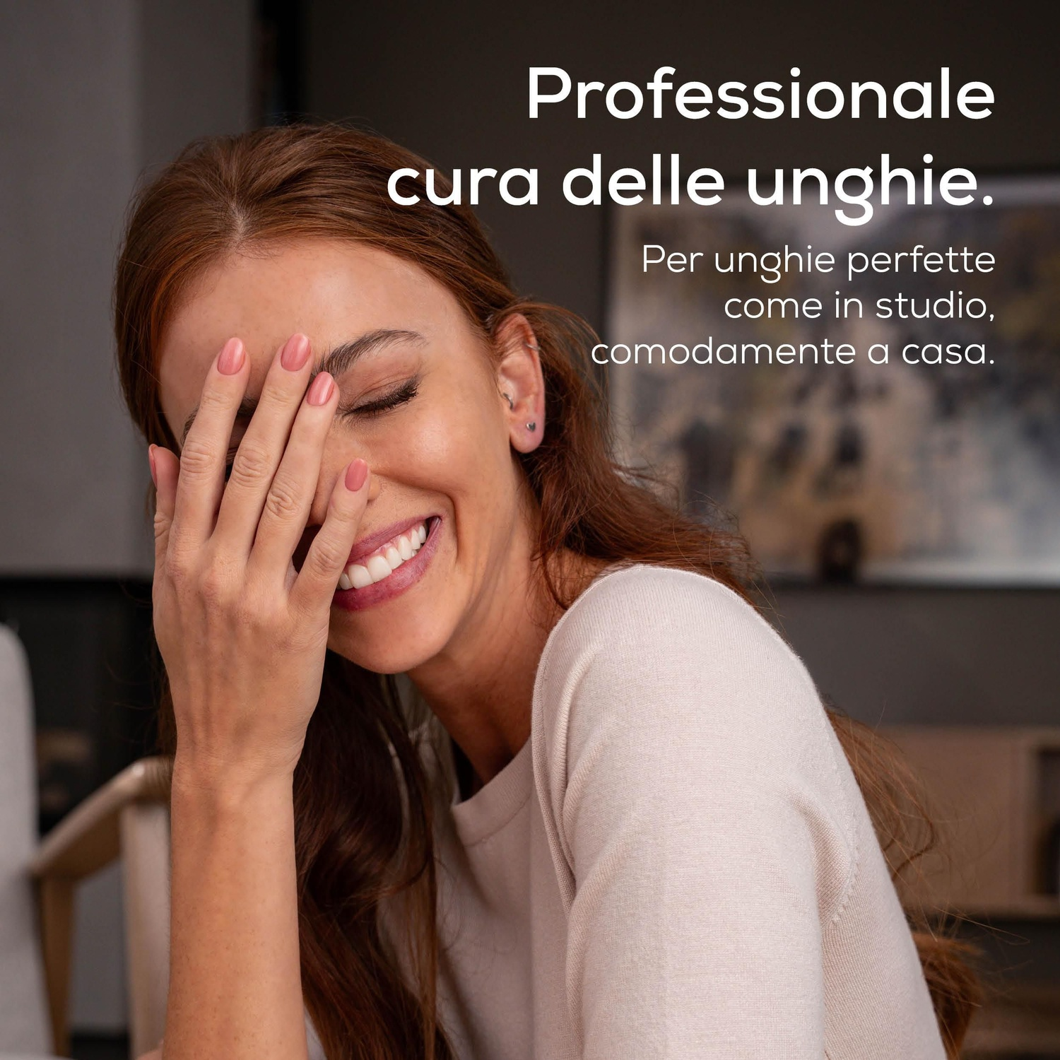 Donna con unghie rosa ride, coprendosi il viso con la mano.