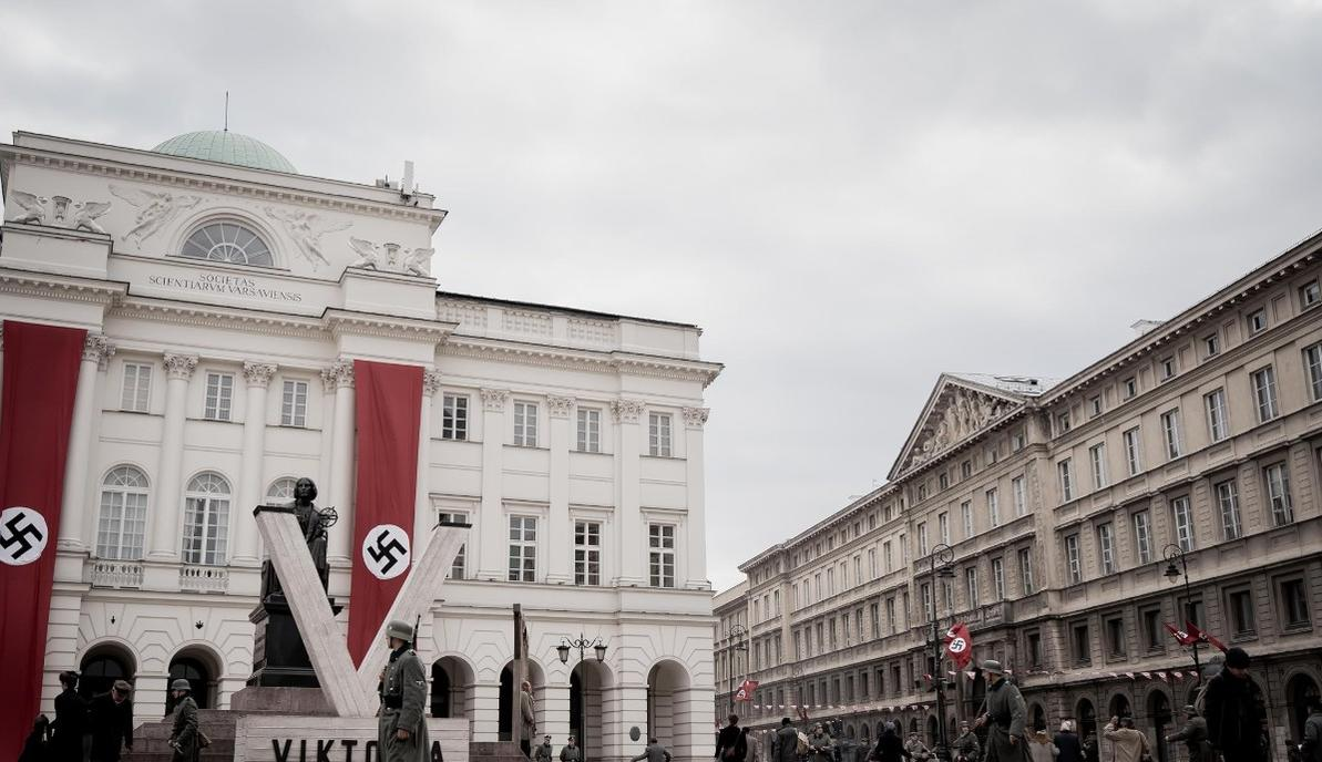 Soldaten stehen vor einem weißen Gebäude mit Hakenkreuz-Bannern.