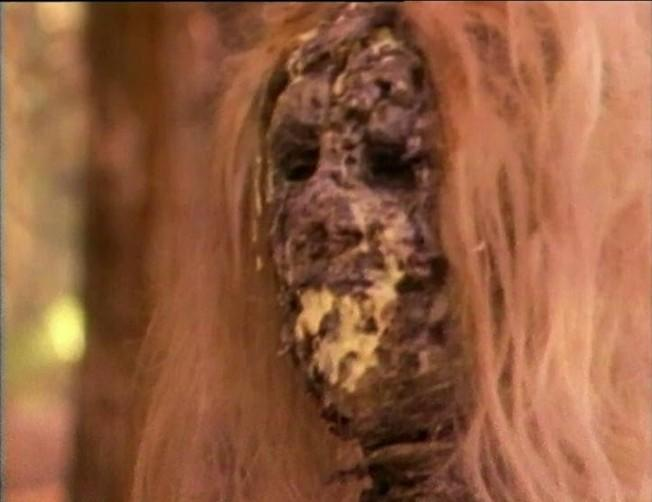 Nahaufnahme eines verrottenden Gesichts mit langen, hellbraunen Haaren.