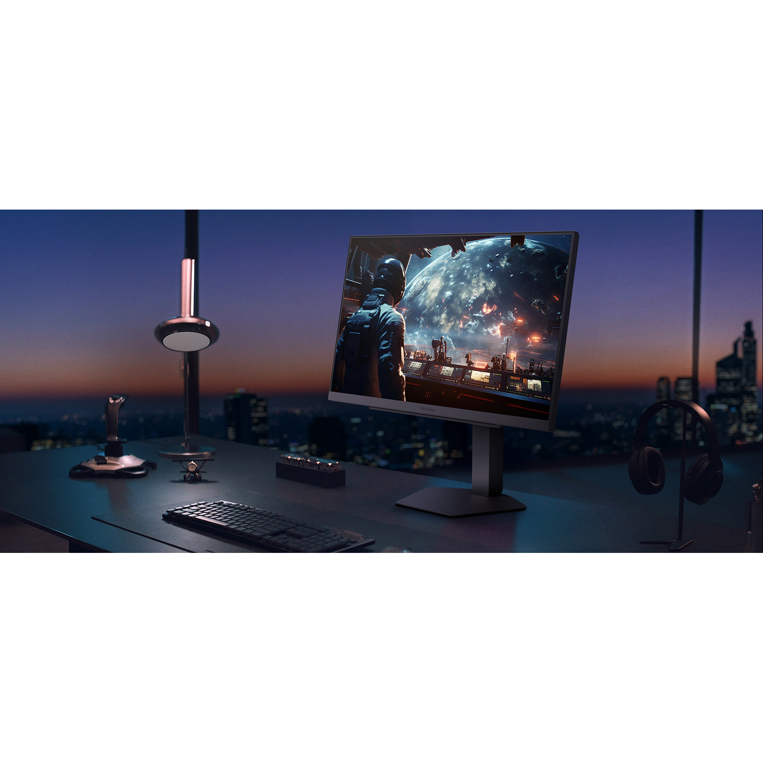 Desk with monitor, keyboard, joystick, and headphones at sunset.