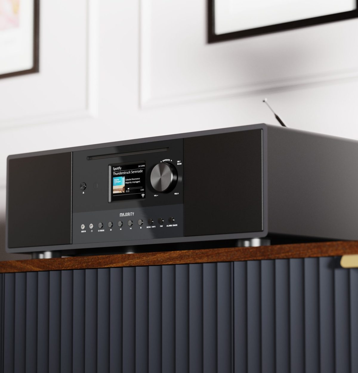 Un système stéréo noir avec écran Spotify posé sur une armoire sombre.