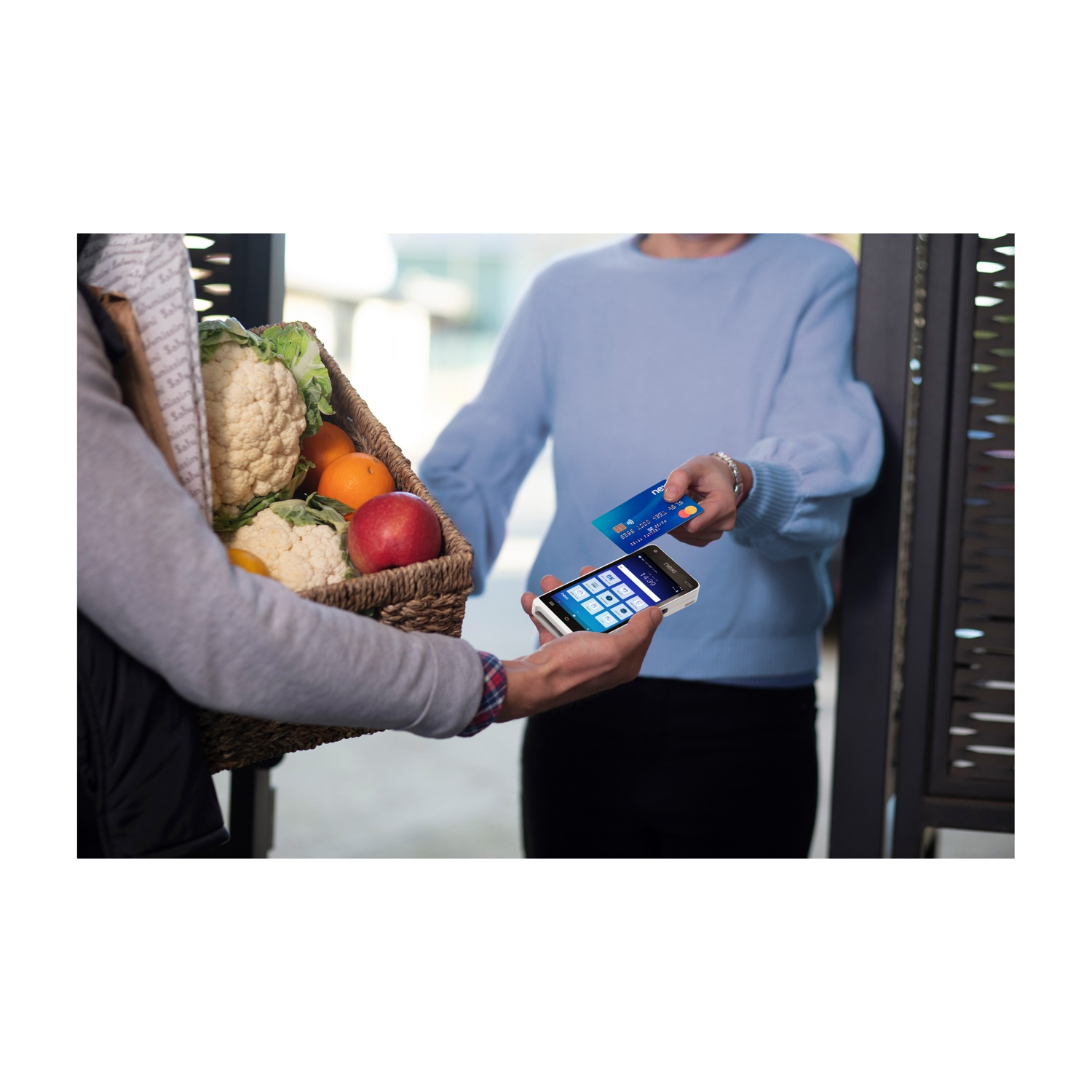 Una persona tiene un cesto di generi alimentari, un'altra paga con carta.