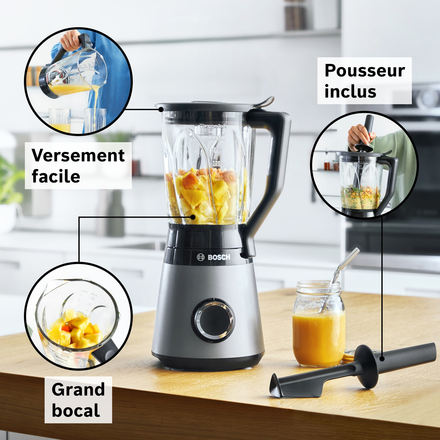 Mixeur gris avec son pot en verre rempli de morceaux de fruits. Accessoires inclus.