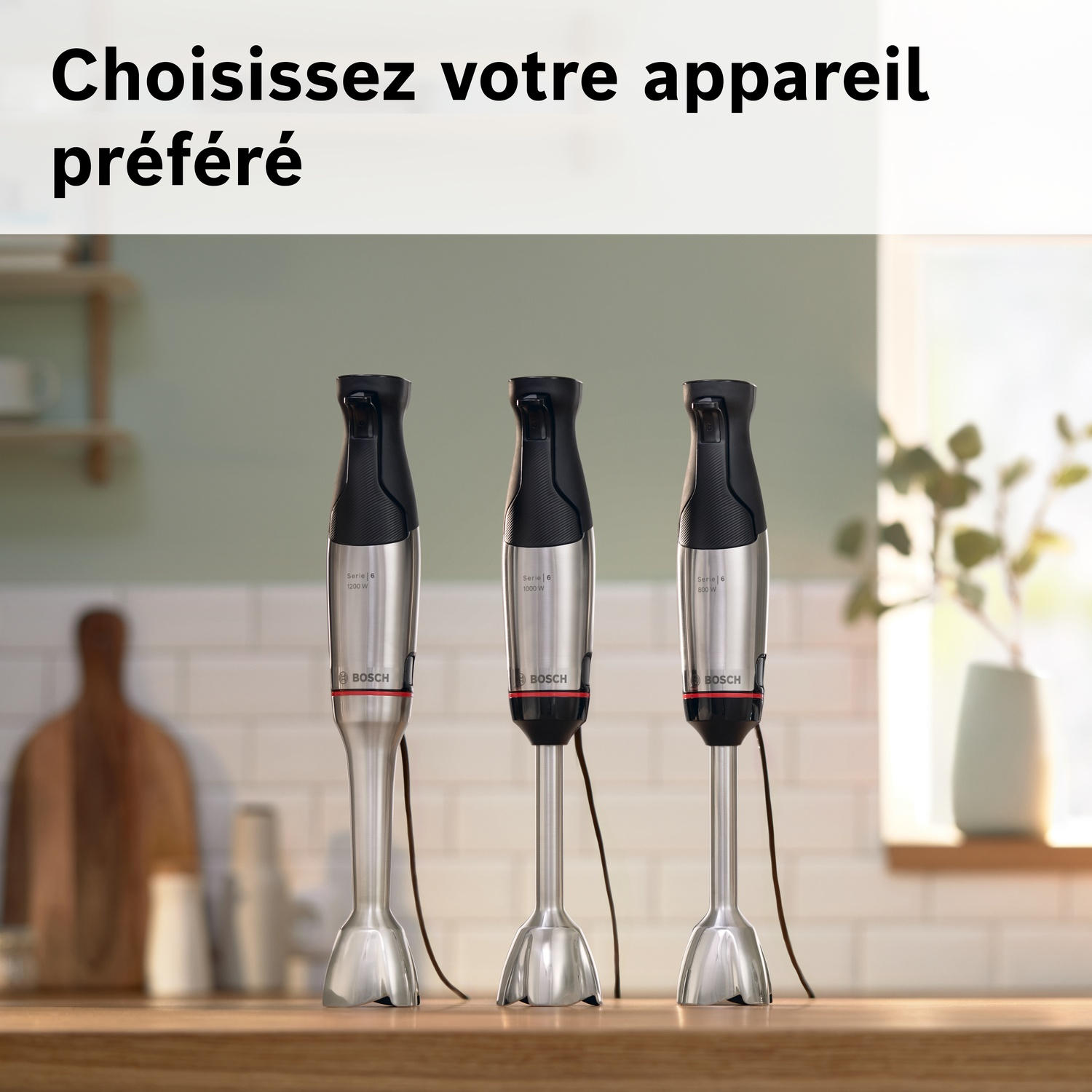 Trois mixeurs plongeants argentés avec poignées noires sur une surface en bois.