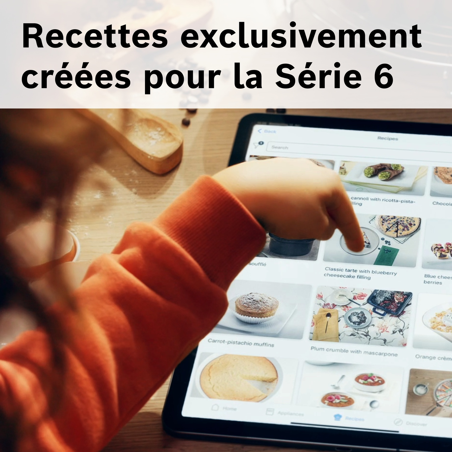 Enfant en pull orange tapant sur une tablette affichant des recettes.