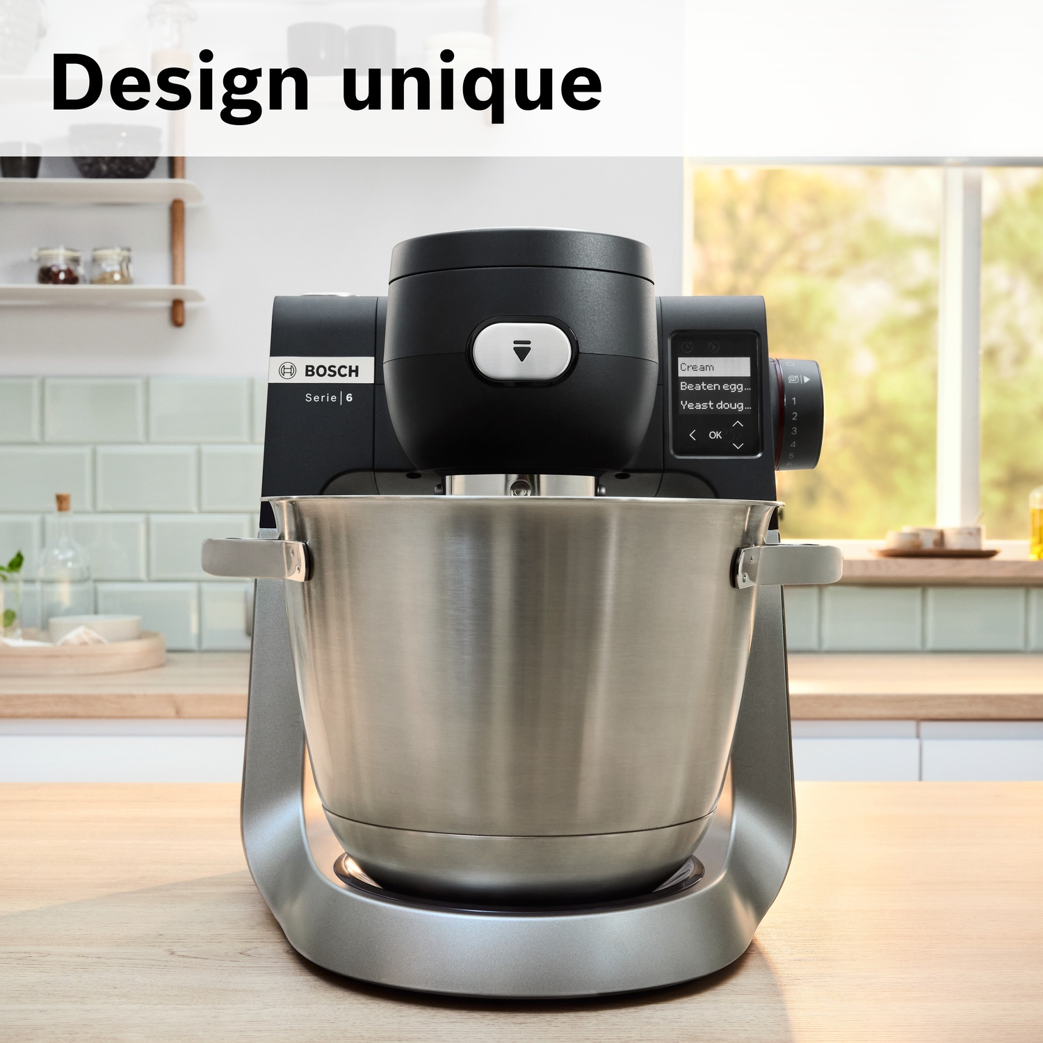 Un robot pâtissier Bosch noir avec bol en inox sur une table en bois.