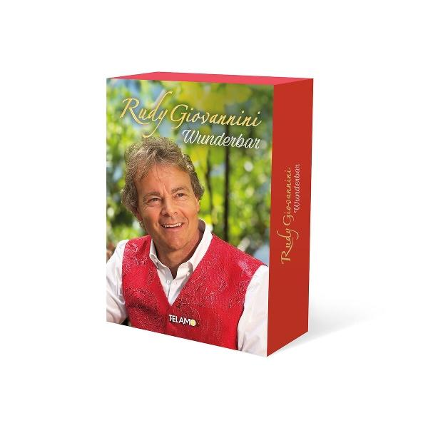 Ein Mann mit roten Weste und weißem Hemd lacht, mit Schriftzug Rudy Giovannini.