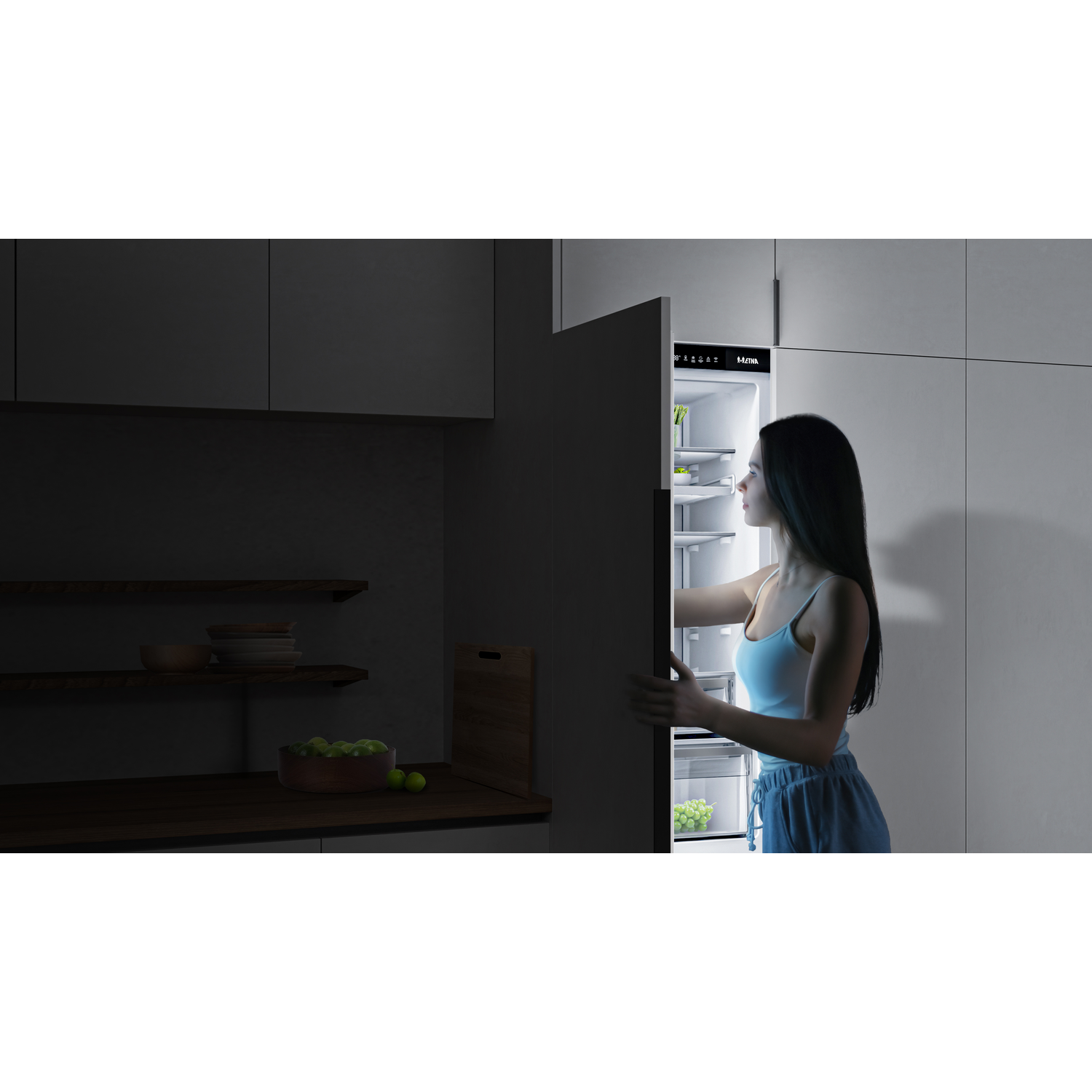 A woman opens a lit refrigerator with food items inside.
