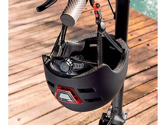 Un casco negro cuelga del manillar de un patinete sobre tablones.