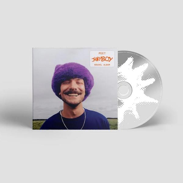 Ein Mann mit violetter Mütze lächelt neben einem CD-Album-Cover.
