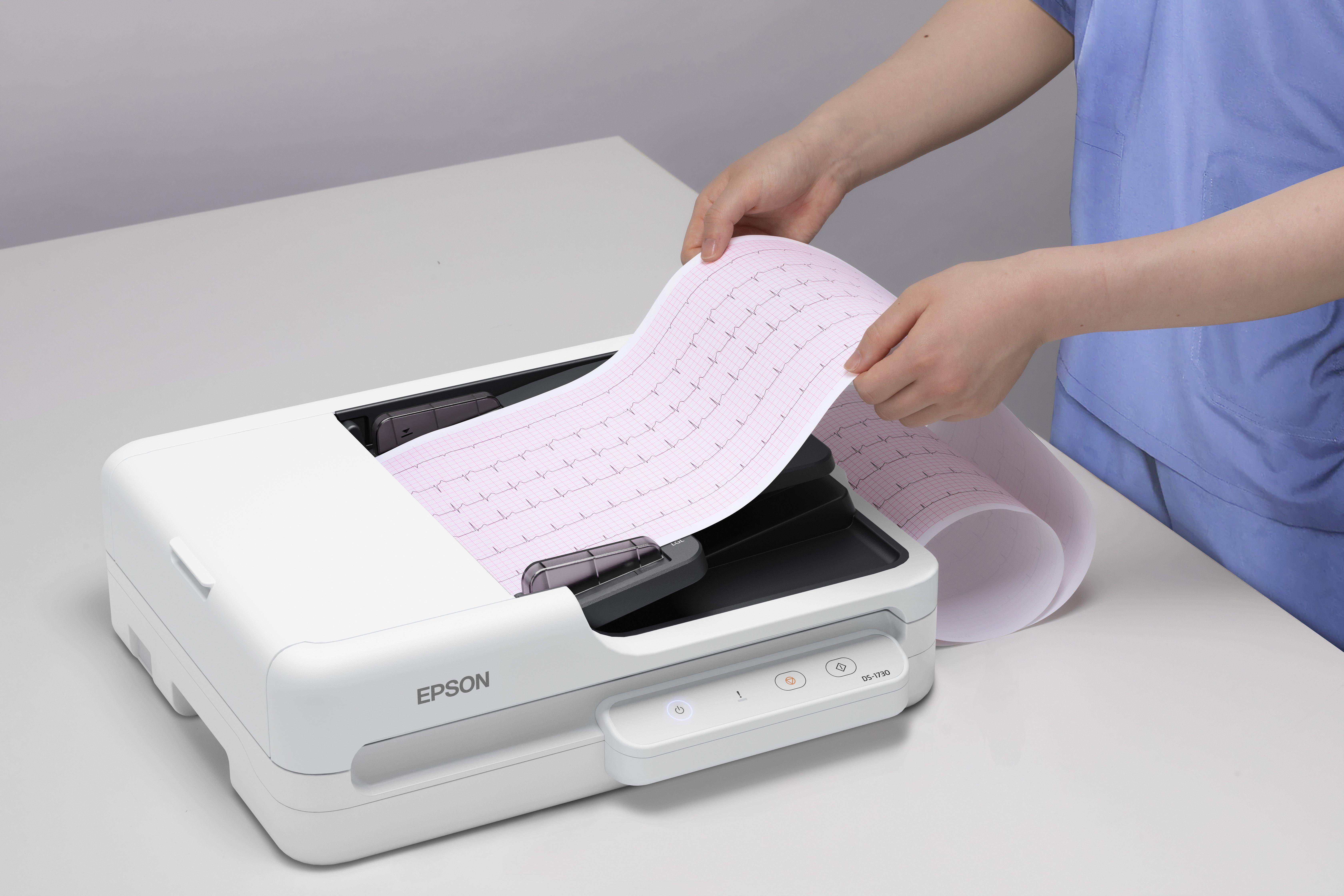 Eine Person in blauer Kleidung hält ein EKG-Papier über einem weißen Epson-Drucker.
