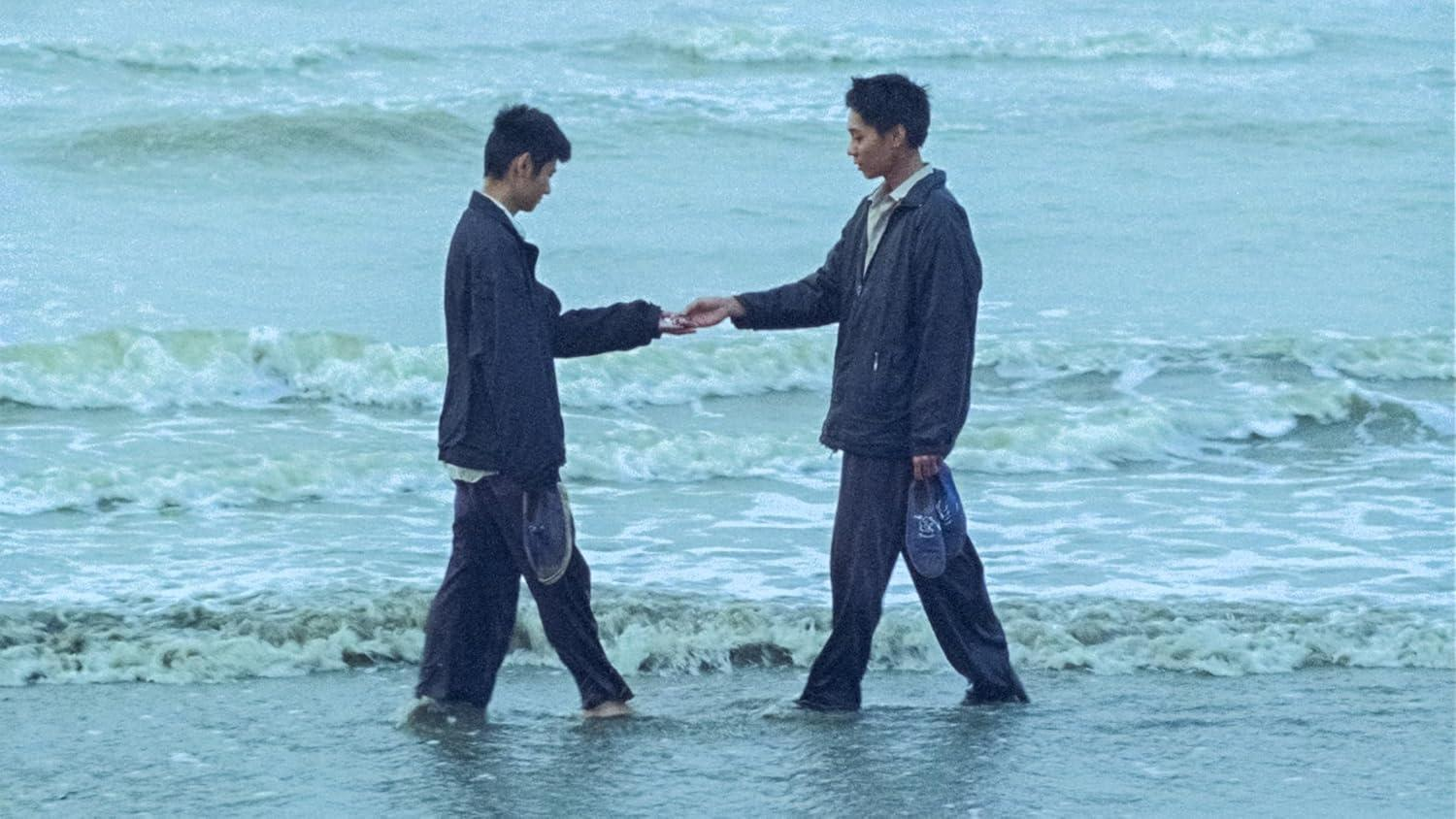 Zwei junge Männer stehen im Meer und reichen sich die Hände.
