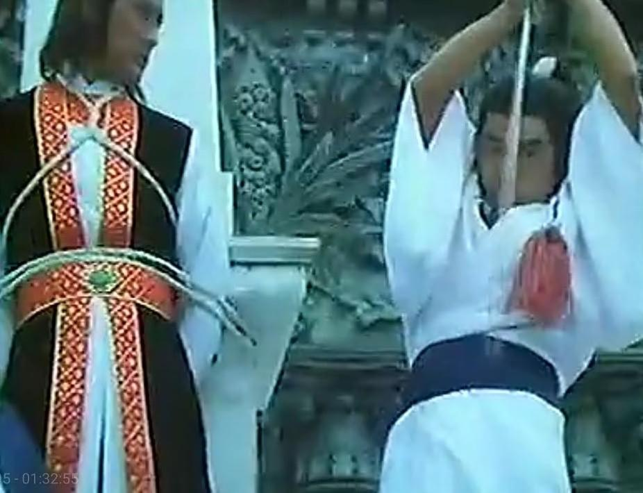Zwei Männer in traditioneller Kleidung, einer mit einem Bogen, der andere mit einem Schwert.