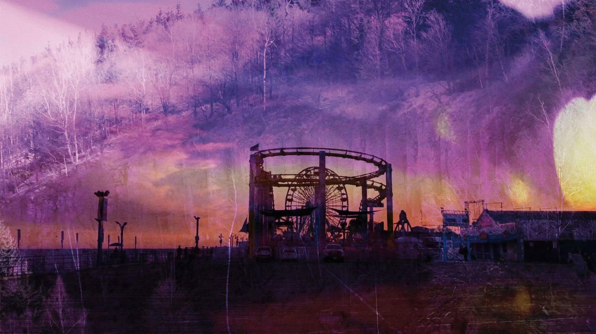 Eine Achterbahn und ein Riesenrad vor einem violetten Himmel mit Bäumen.