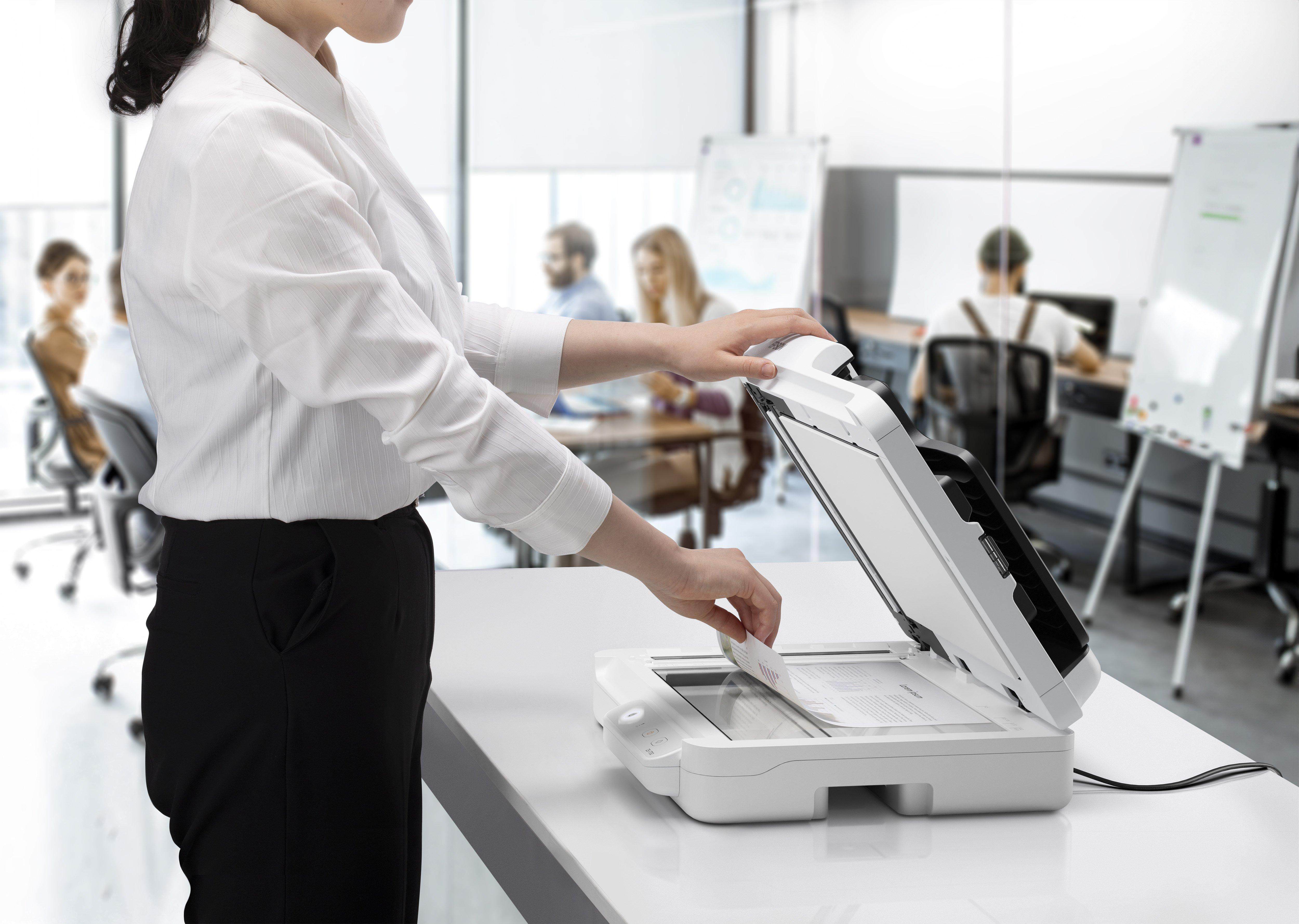 Eine Frau im weißen Hemd scannt ein Dokument in einem Büro.