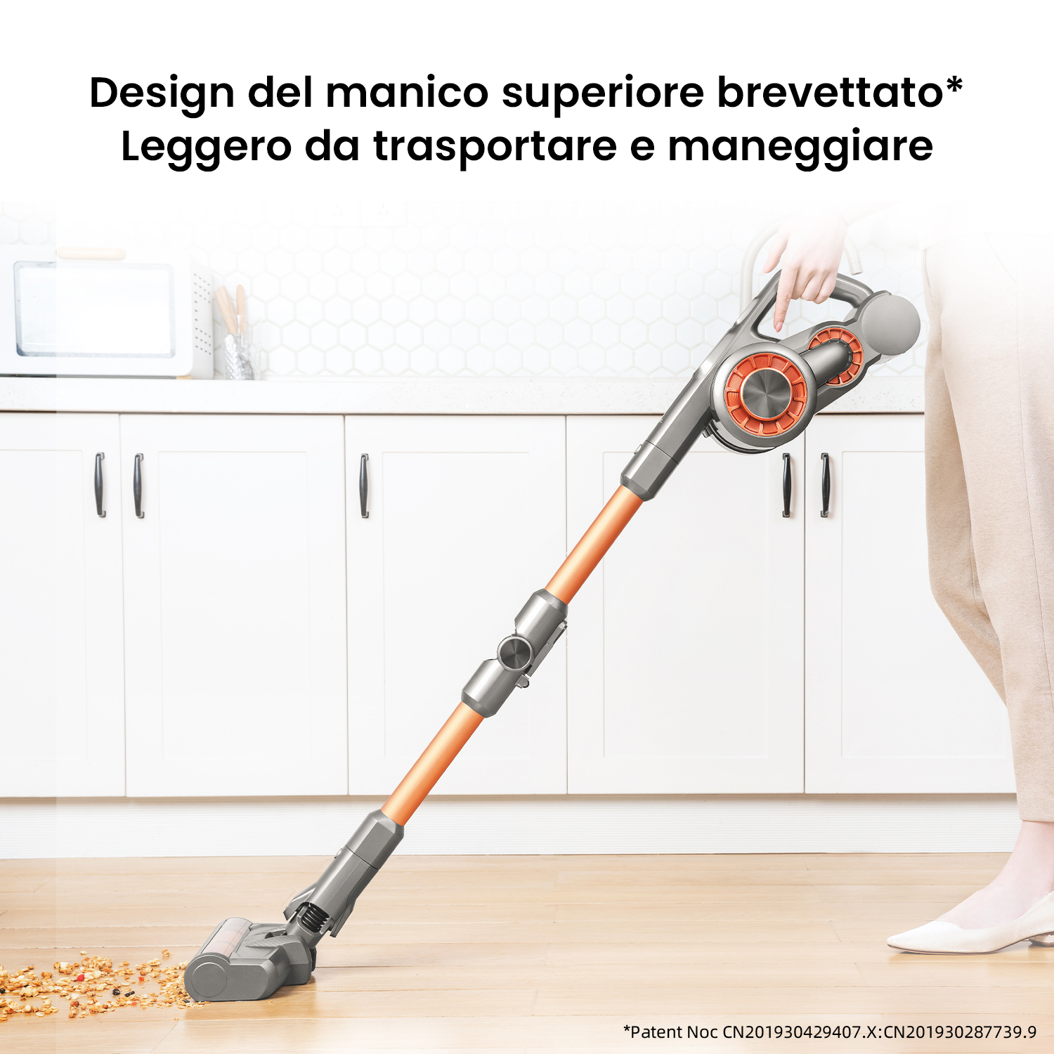 Un aspirapolvere leggero e portatile con manico arancione pulisce un pavimento in legno.