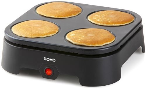 A black appliance with four golden-brown pancakes cooking.