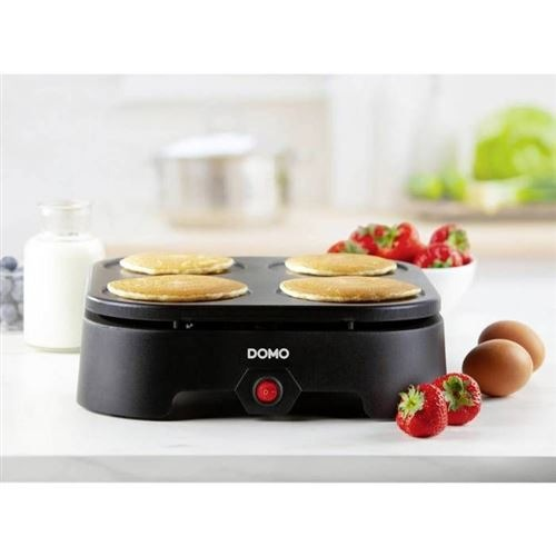 Black DOMO pancake maker with 4 pancakes, strawberries, and eggs.