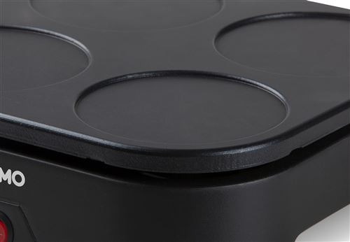 Close-up of a black electric pancake maker with four circular indentations.