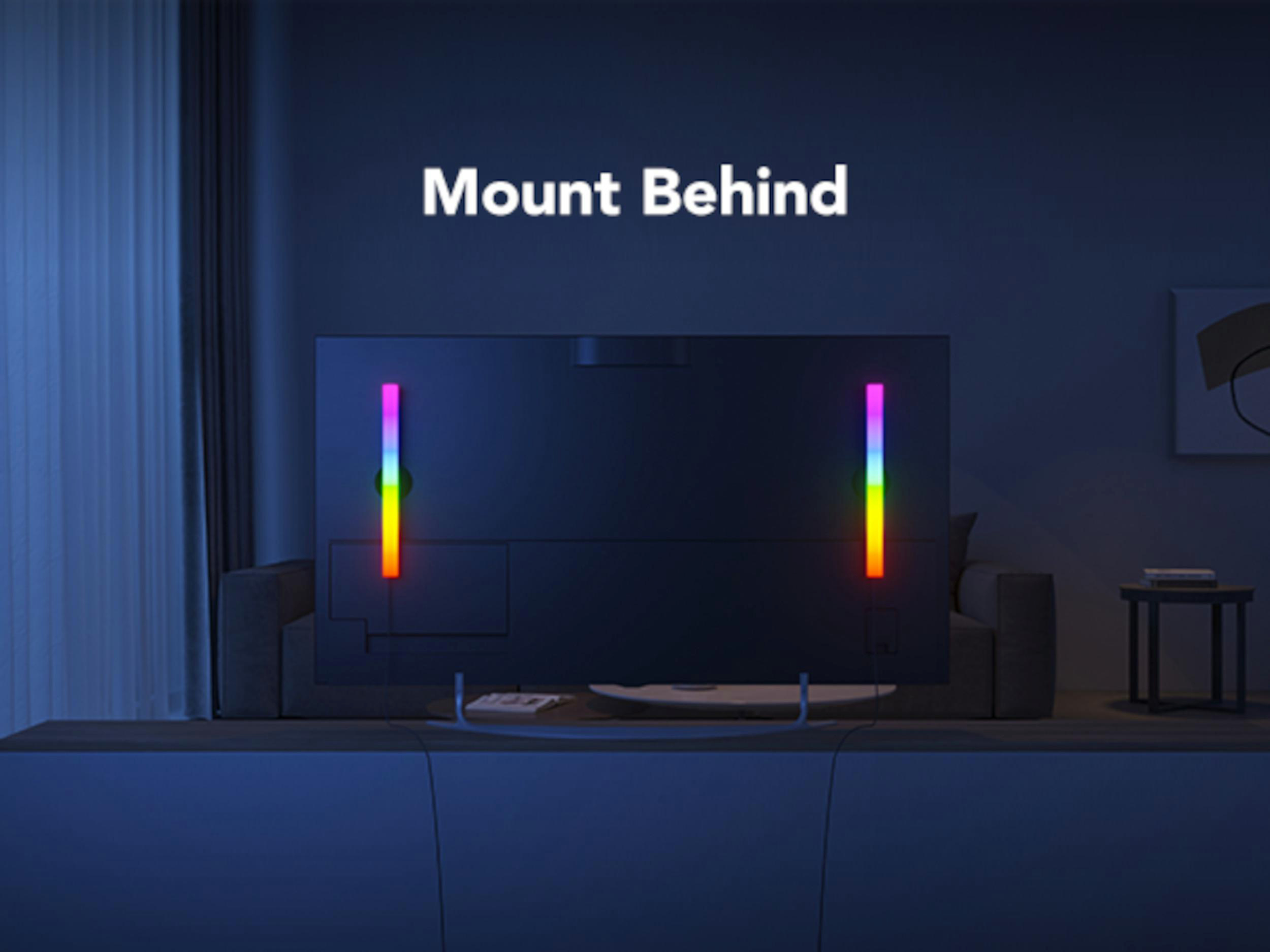 Ein Fernseher mit Lichterstäben in Regenbogenfarben hinter dem Sofa.