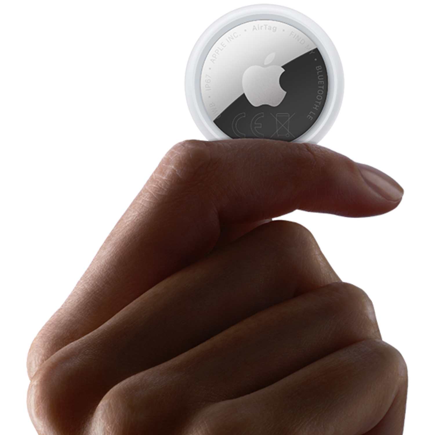 A finger holds a white Apple AirTag with a silver back.