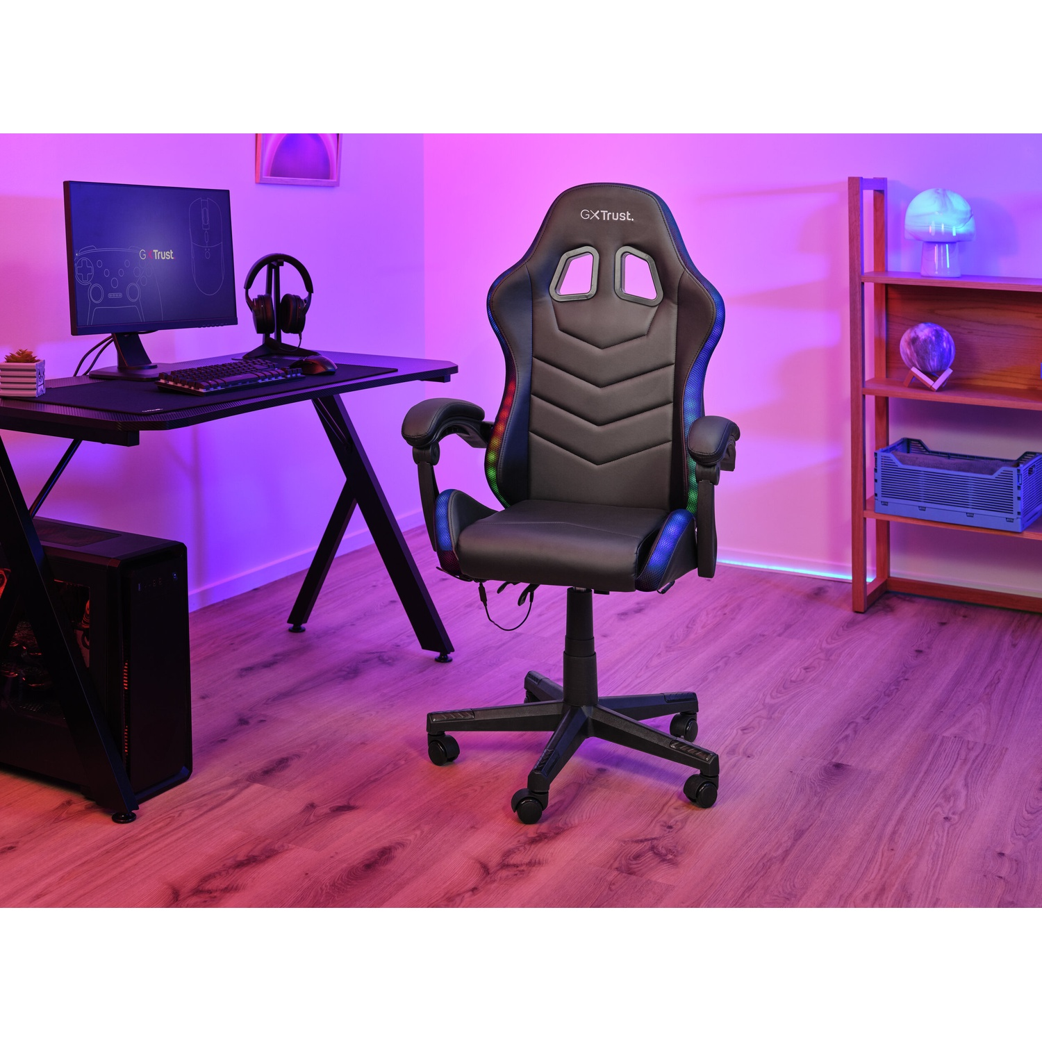 Una sedia da gaming nera con illuminazione RGB si trova davanti a una scrivania con computer e monitor.