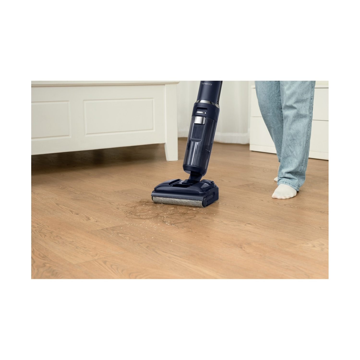 Una persona aspira un pavimento in legno con un aspirapolvere blu.