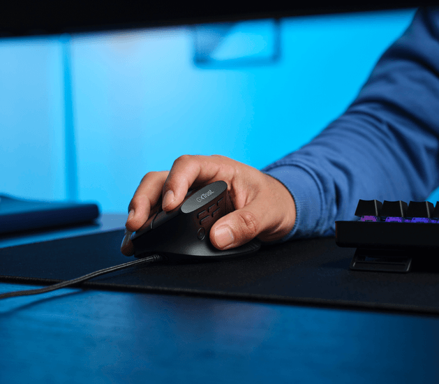 Egy kéz fog egy fekete ergonomikus egeret egy kék hátterű asztalon.
