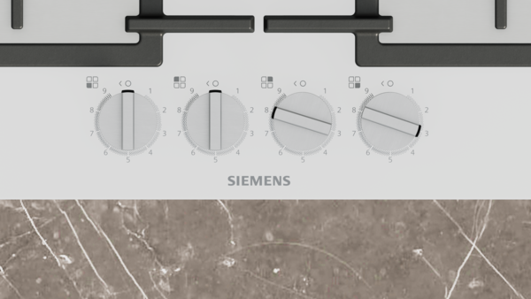 Mermer yüzeyli, dört düğmeli beyaz Siemens ocak üstünün yakın çekimi.