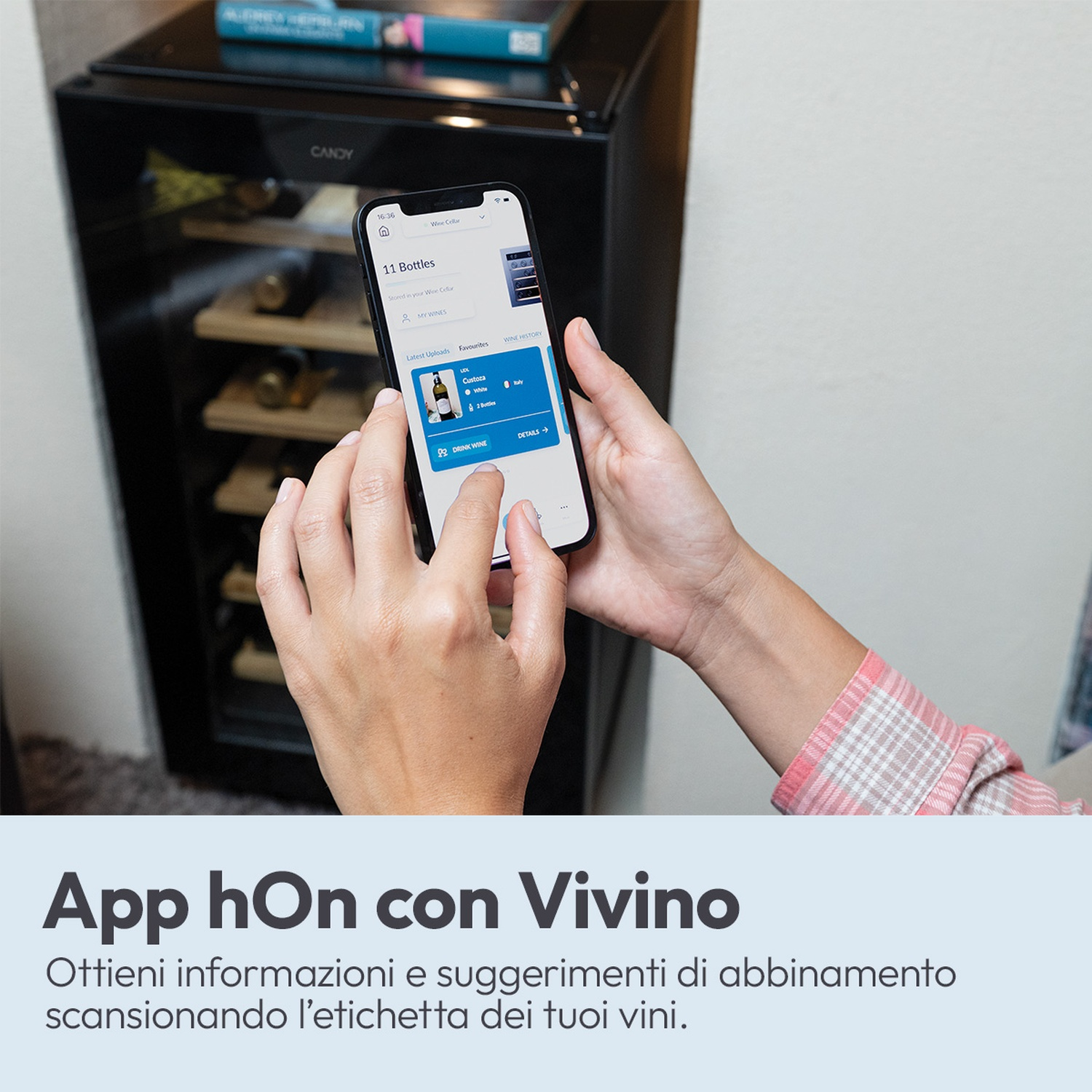 Una persona tiene uno smartphone davanti a un frigorifero per vino con bottiglie.