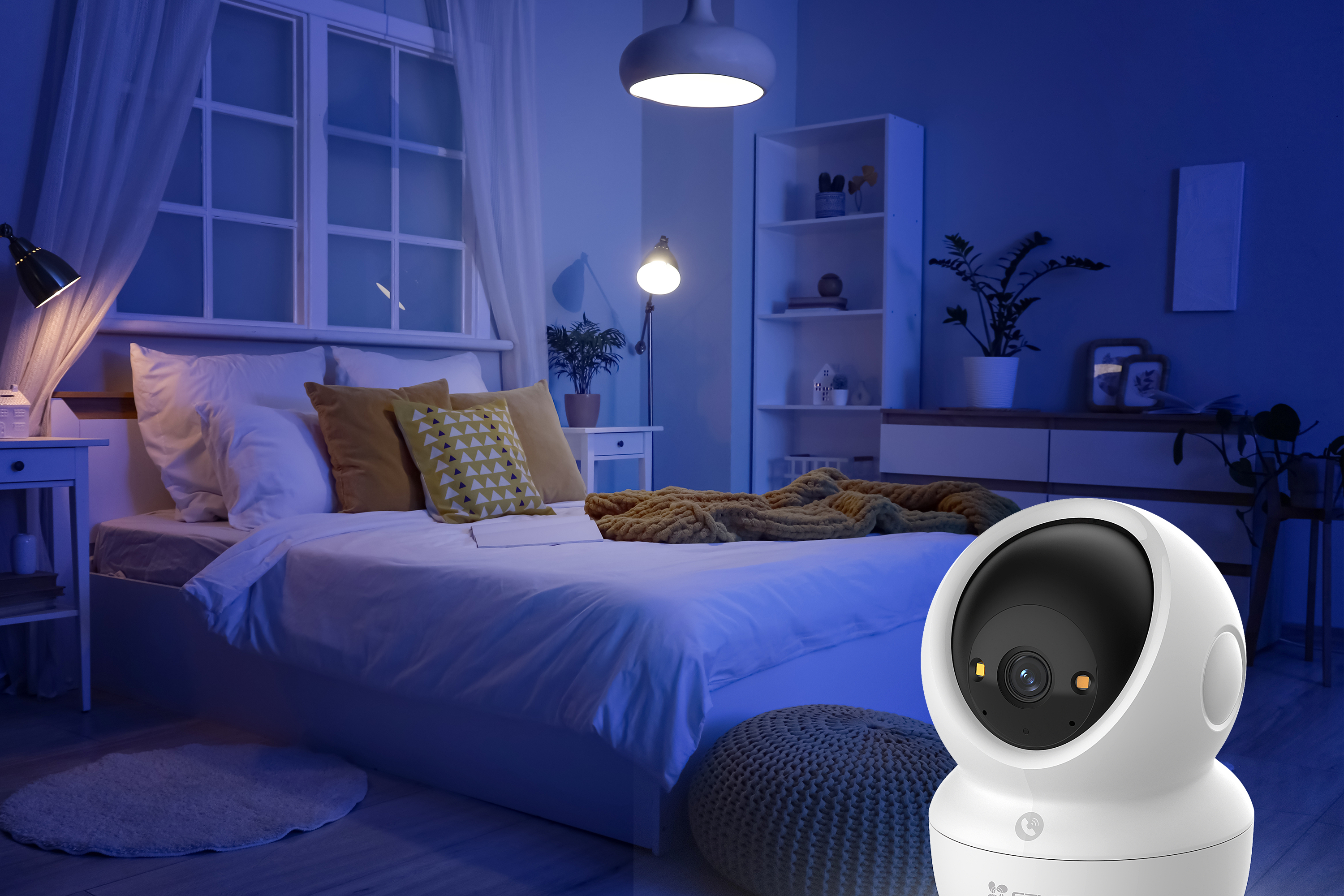 Ein weißer Überwachungs-Kamera steht vor einem Bett in einem blauen Schlafzimmer.