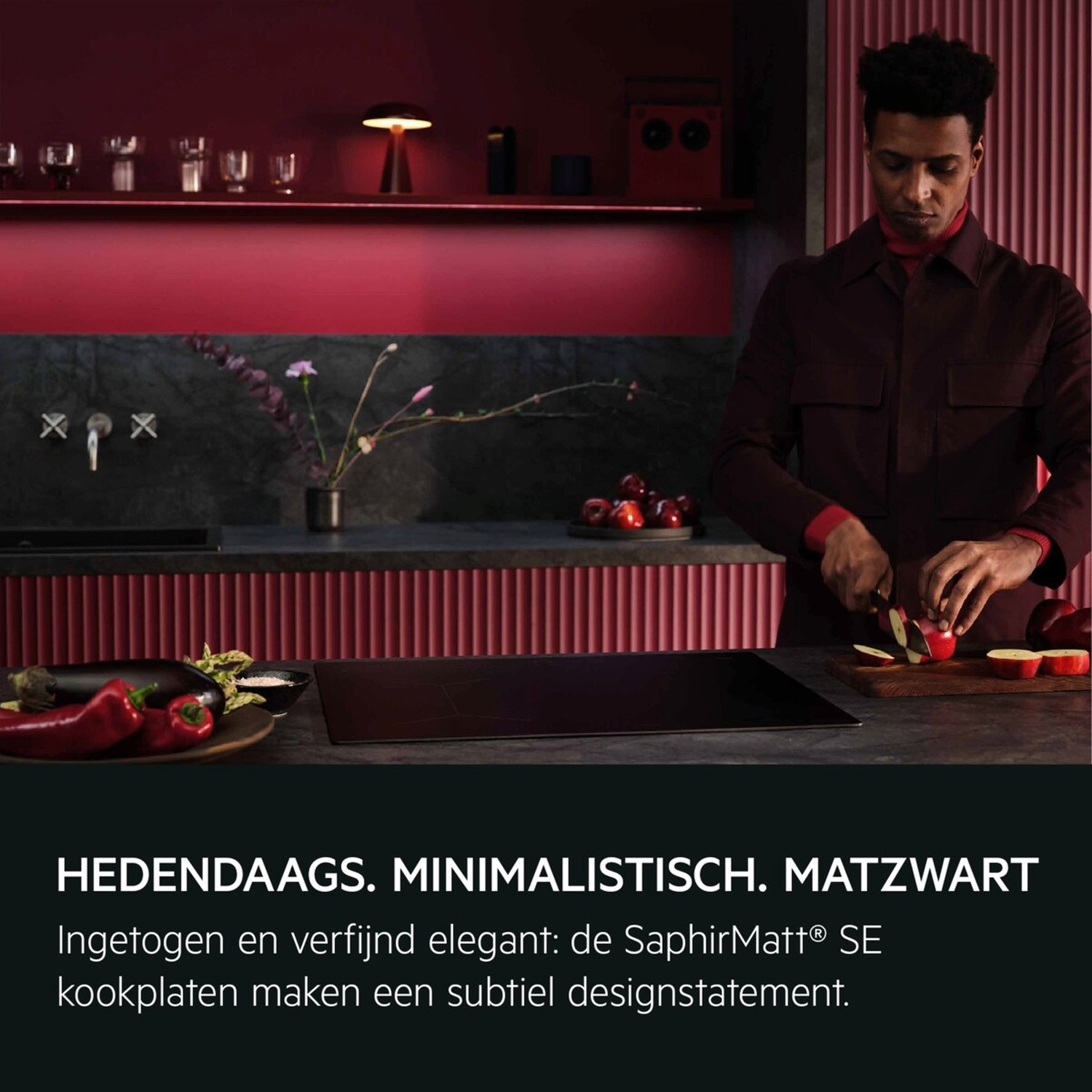 A man cuts apples in a modern kitchen with red wall paneling.