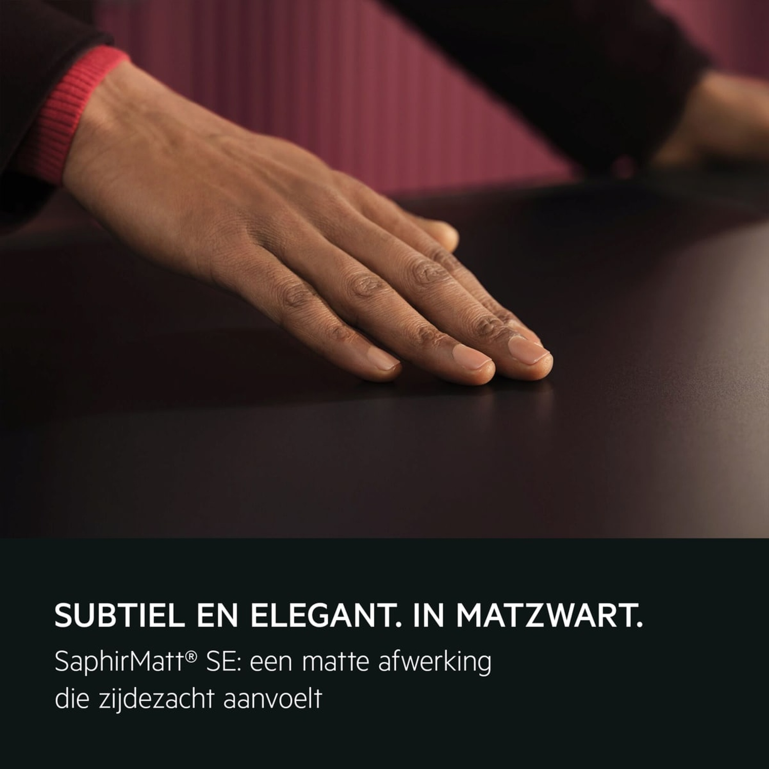 Une main avec un revers de manche rouge repose sur une surface noire mate.