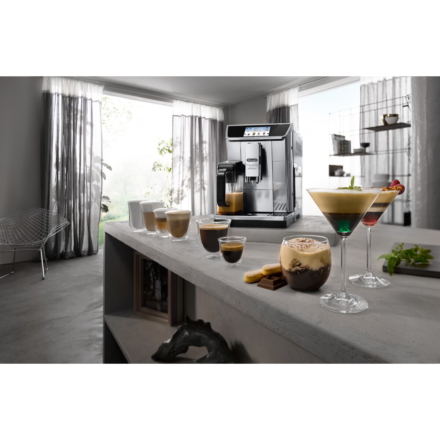 Koffiezetapparaat met glazen, cocktails en koekjes op een betonnen aanrecht.