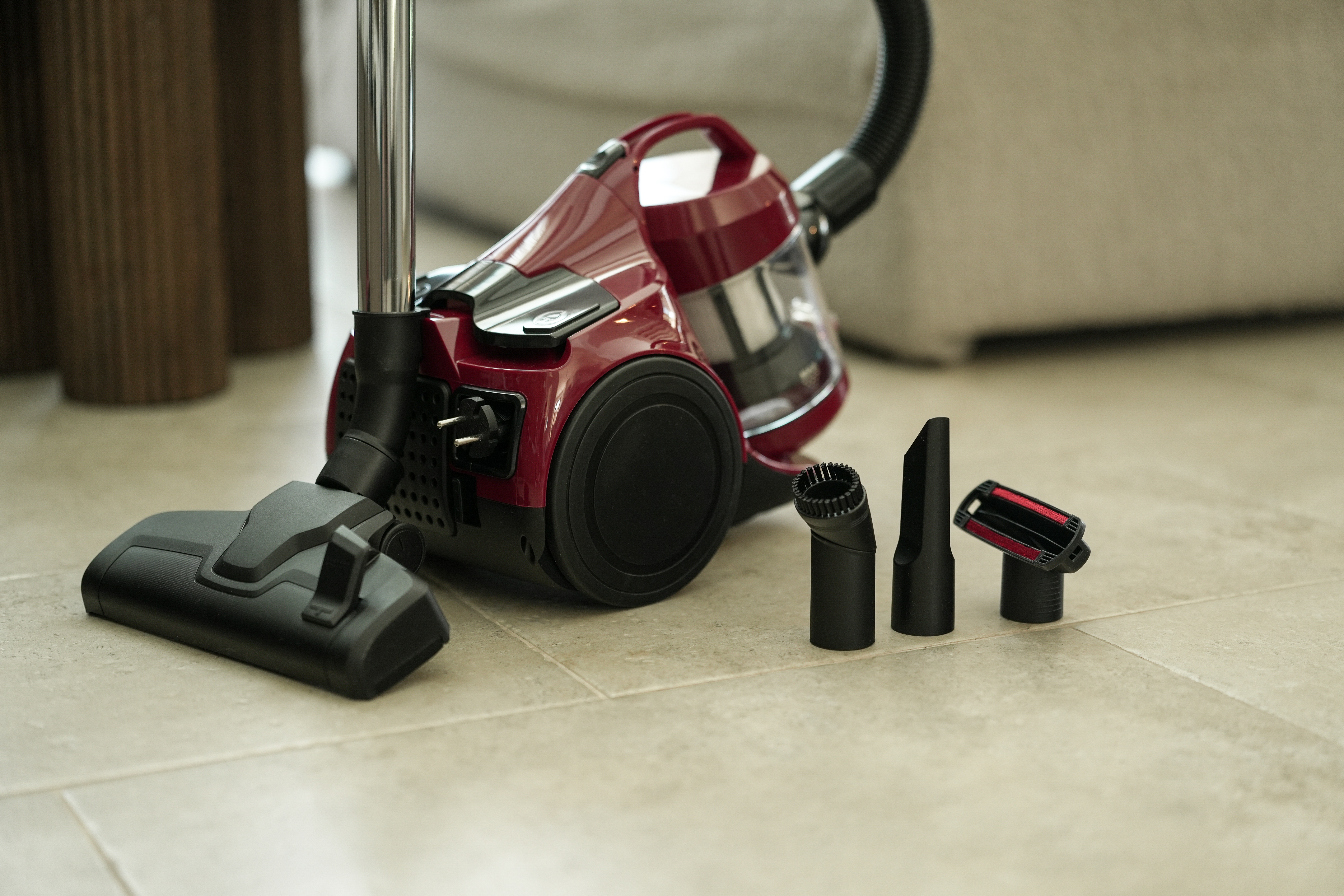 Czerwony odkurzacz z akcesoriami na podłodze wyłożonej płytkami.