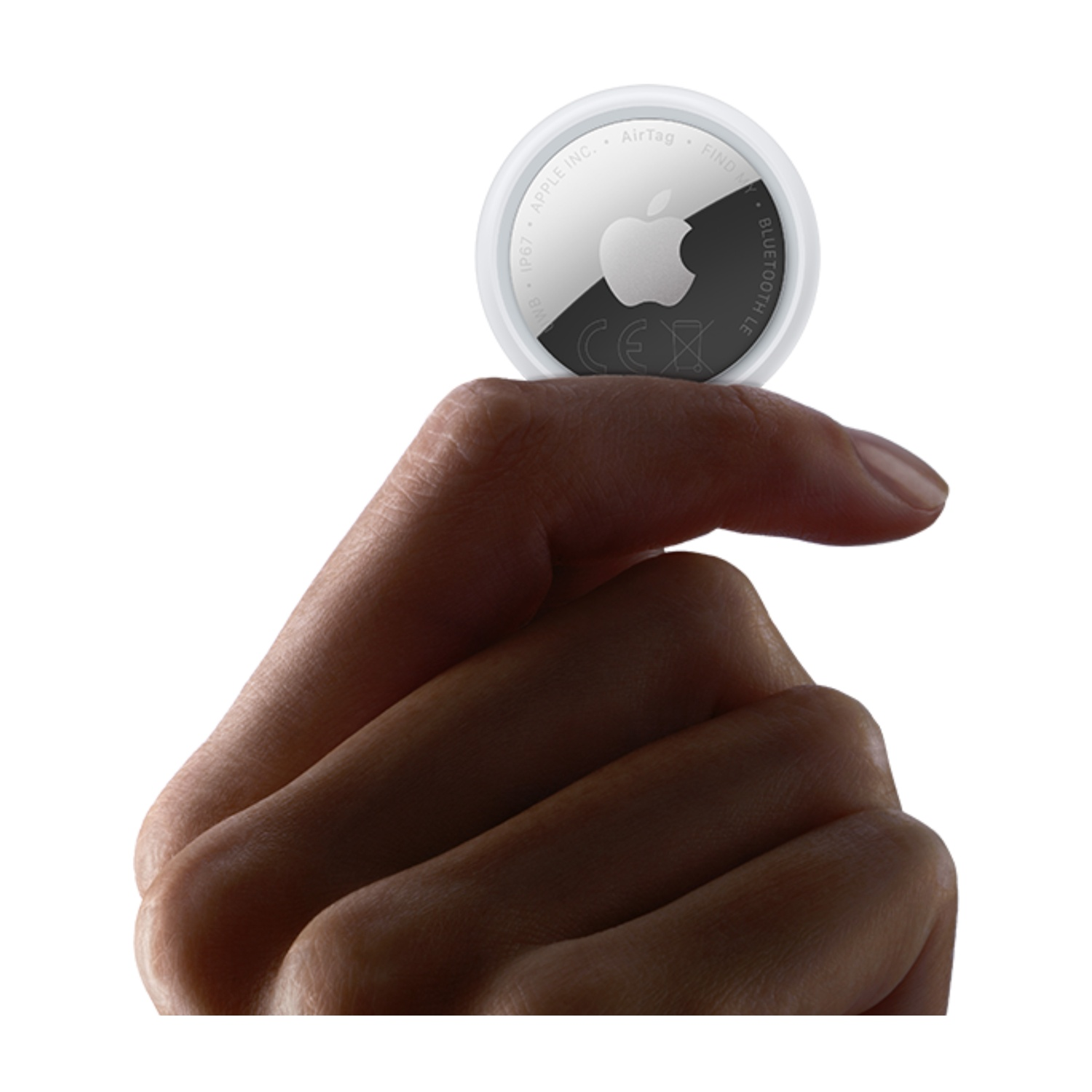 Una mano tiene un AirTag Apple bianco con il logo Apple.