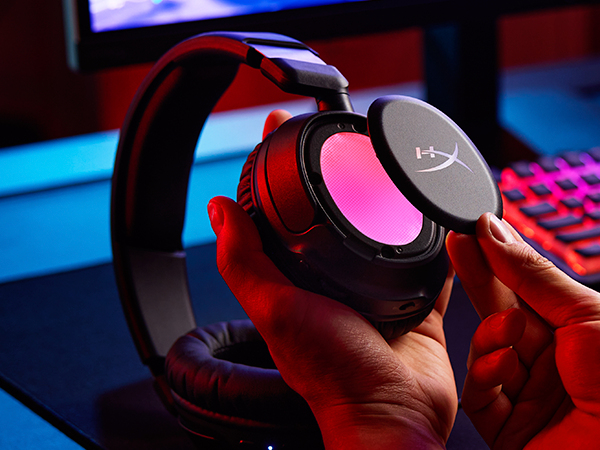 Una mano sujeta unos auriculares con almohadillas rosas brillantes. Se retira una pieza desmontable.