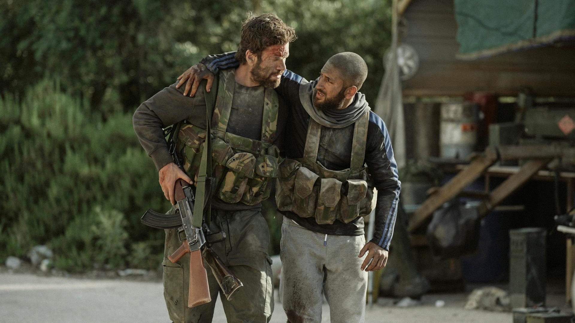 Zwei Soldaten mit Kampfmitteln und Waffen stützen sich gegenseitig.