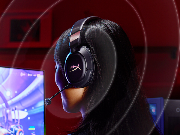 Una persona con auriculares frente a una pantalla de ordenador, con iluminación de fondo roja.