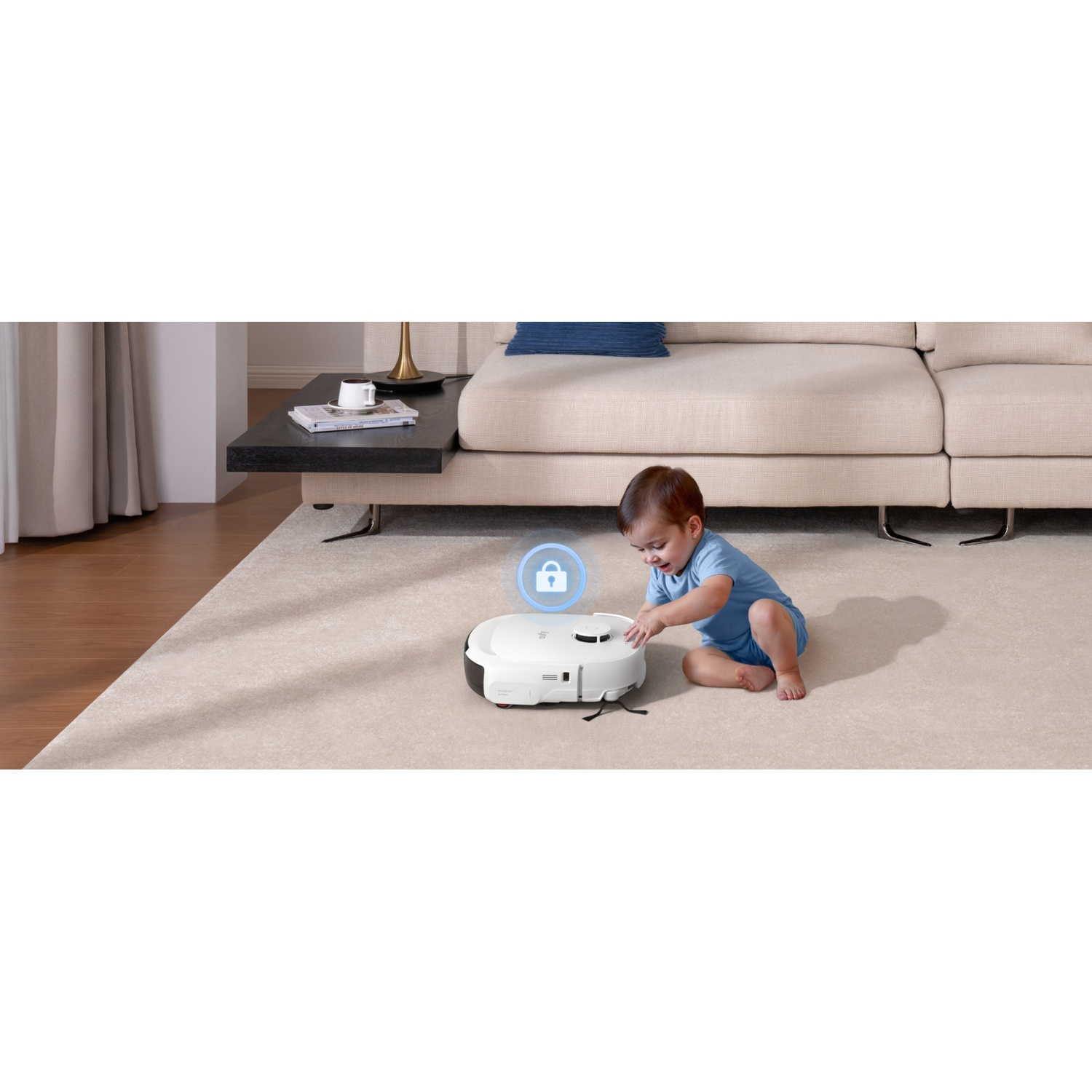 Un bébé en bleu joue avec un robot aspirateur blanc sur un tapis clair.